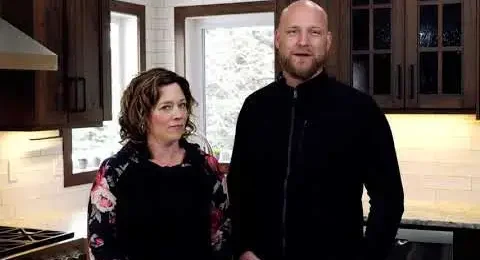 A happy couple standing in their beautifully finished kitchen, enjoying the craftsmanship and warm design of their new space.
