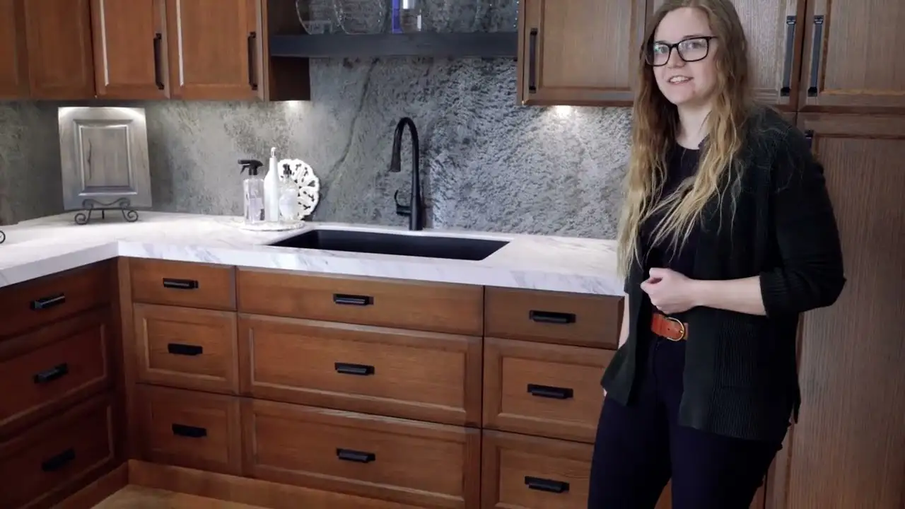 Woman explaining custom cabinets in a showroom with detailed wood cabinet doors and handcrafted woodwork samples displayed on the counter.