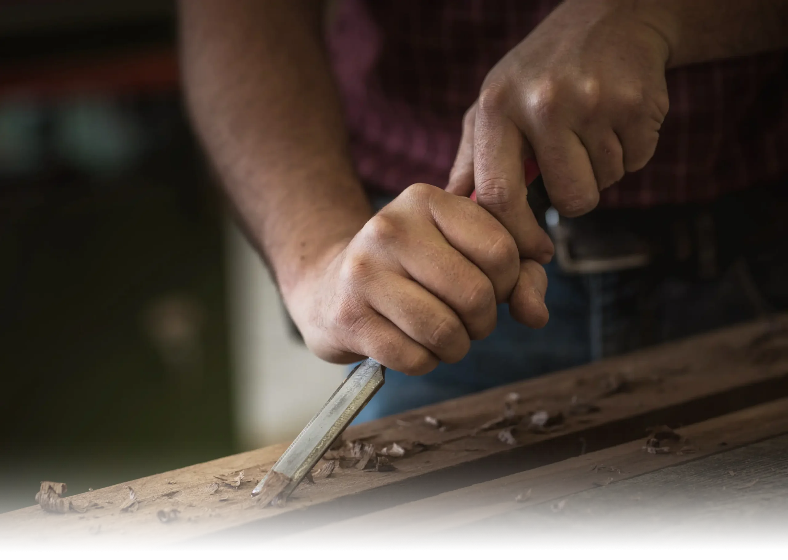 Woodworker hand-chiseling hardwood to shape detailed components for custom cabinetry with precision craftsmanship.