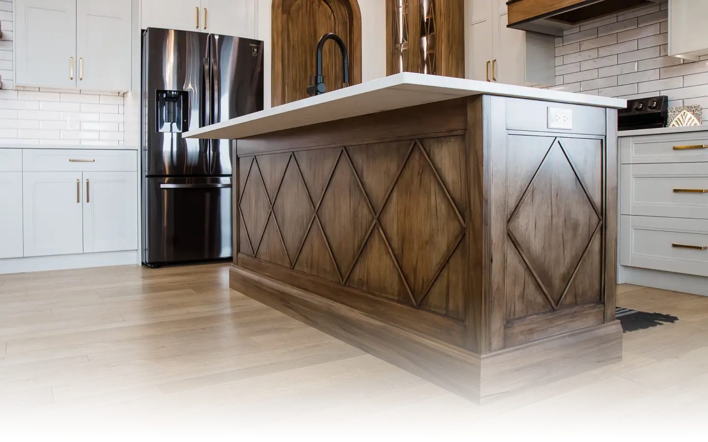 Custom wood kitchen island with diamond-pattern millwork and premium cabinetry craftsmanship by Hiebert Cabinets, featuring white countertops and surrounding built-in kitchen cabinets.
