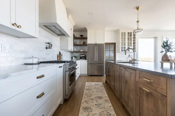 Bright custom kitchen featuring white upper cabinets, wood island cabinetry, built-in shelving, and premium millwork crafted by Hiebert Cabinets.