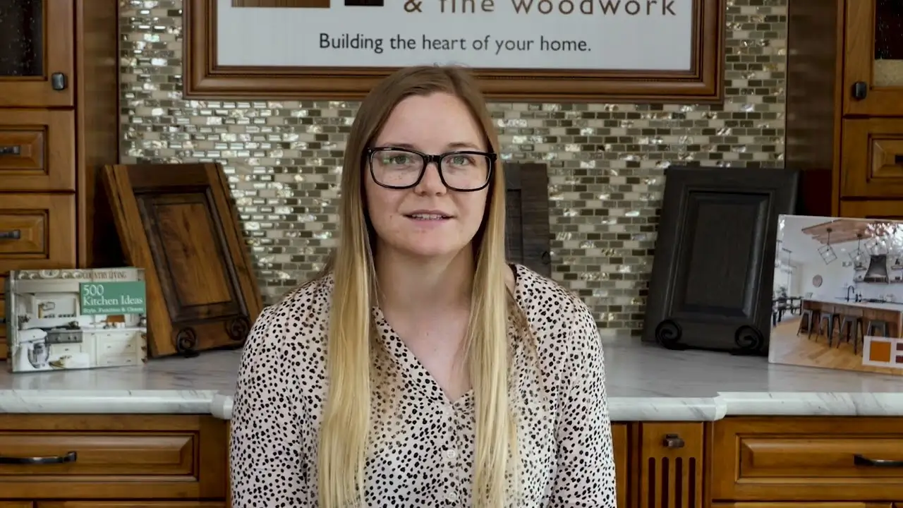 Customer sitting in a showroom surrounded by custom wood cabinets and handcrafted cabinet door samples, showcasing detailed fine woodwork craftsmanship.