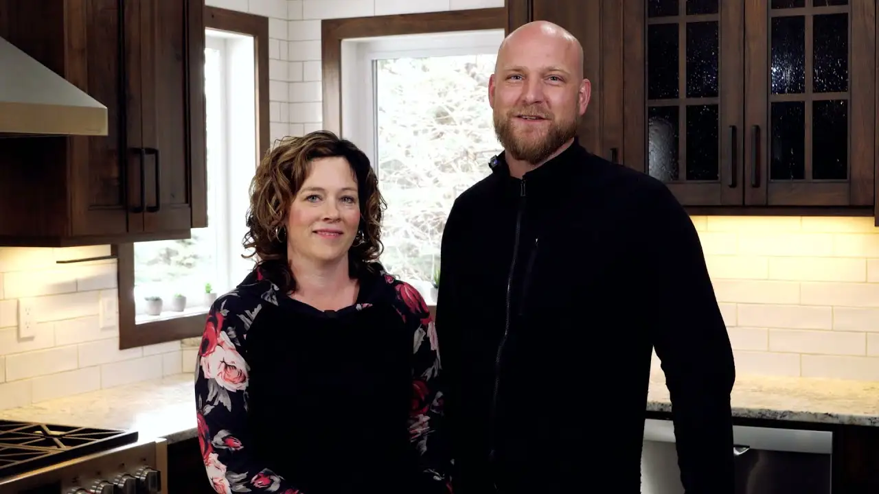 A happy couple standing in their beautifully finished kitchen, enjoying the craftsmanship and warm design of their new space.