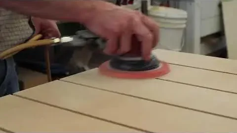 Woodworker sanding a custom cabinet panel with a power sander to achieve a smooth, high-quality finish for Hiebert Cabinets.