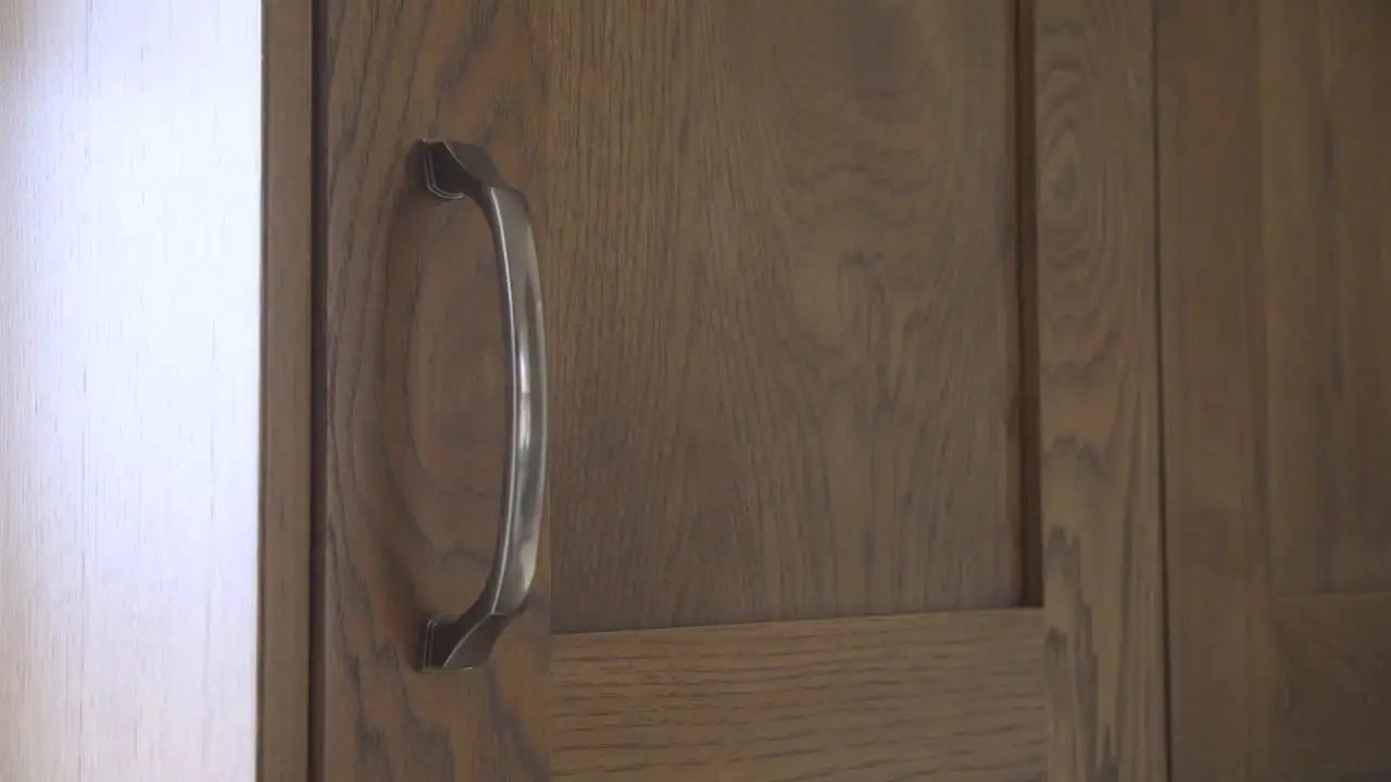Close-up of a custom wood cabinet door with visible grain patterns and a brushed metal handle, showcasing Hiebert Cabinets’ fine craftsmanship.