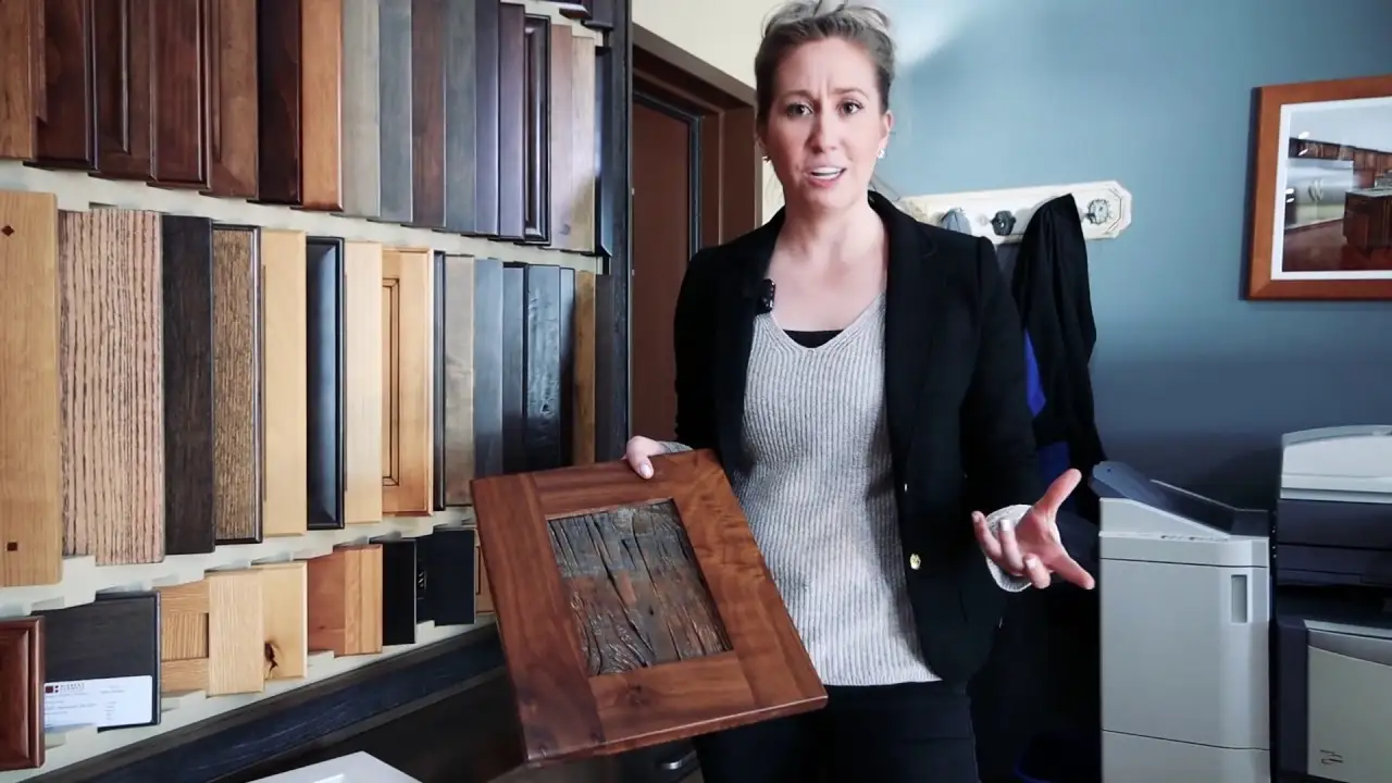 Showroom display of custom cabinet door samples with a designer holding a handcrafted wood cabinet door, highlighting Hiebert Cabinets’ material options and fine woodwork